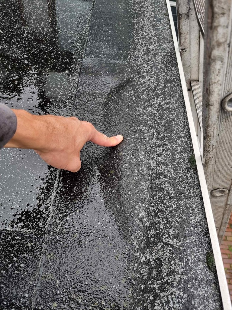 Dakdekker controleert de naden van een bitumen plat dak